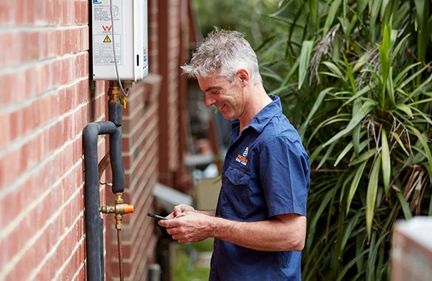 Professional plumber servicing an external hot water system